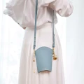Pastellblaue kleine Goji-Tasche mit Riemen aus der veganen Goji-Taschenkollektion von ORSKA Jewelry bei einem Fotoshooting mit Katarzyna Zajączkowska