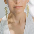 Lange, goldene Ohrringe aus der Thuja-Kollektion von ORSKA Jewelry